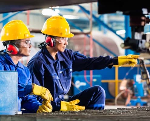 Two engineers look over equipment while one points something out