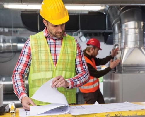 a worker looking at printed plans at the work site