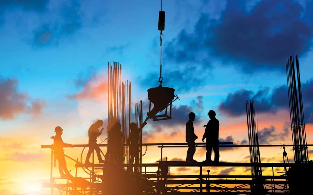 workers on a structure under construction with the sunset in the background