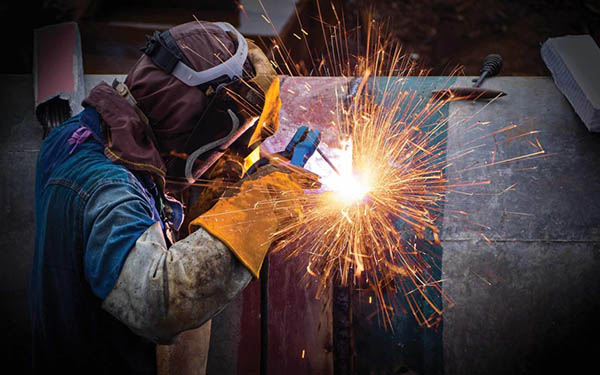 welder performs repairs while sparks fly