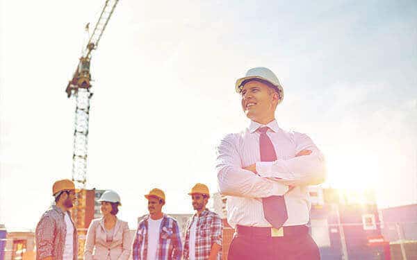 Self assured man stands in front of happy workers