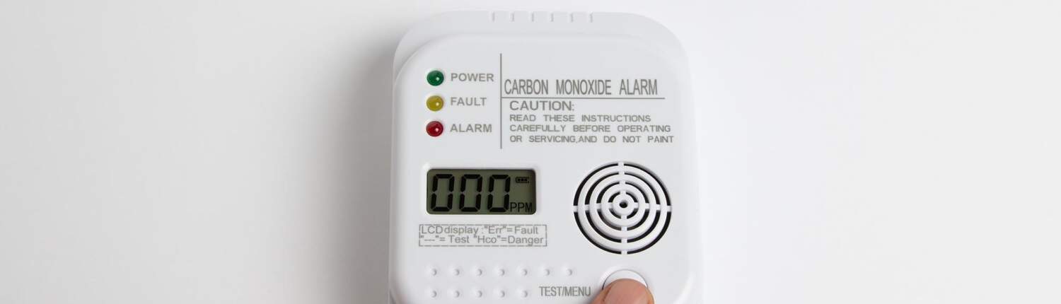 someone pressing a button on a carbon monoxide detector