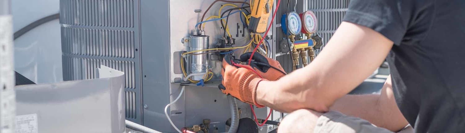 HVAC technician working on controls of air conditioner