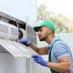 Professional technician maintaining modern air conditioner indoors