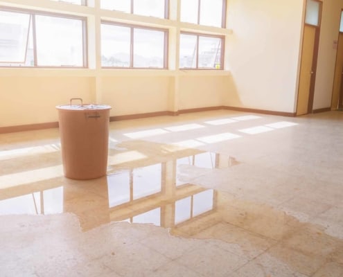 water leak drop interior office building in red bucket from Ceiling and flow on terrazzo floor