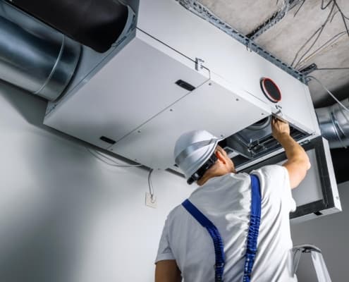 Back view of a man doing maintenance on an HVAC unit