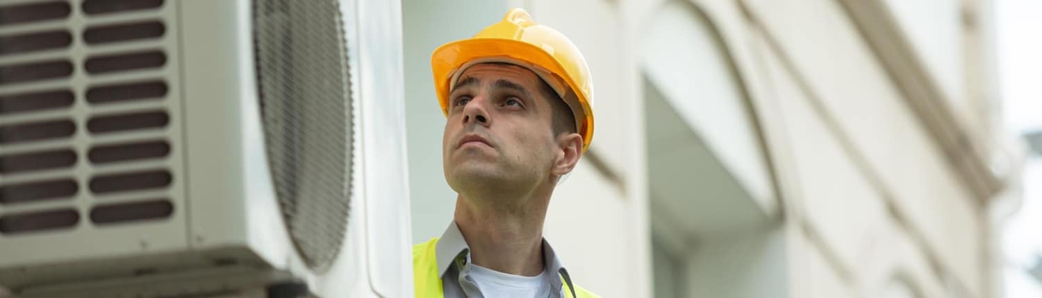 Front view of a man looking at an HVAC unit