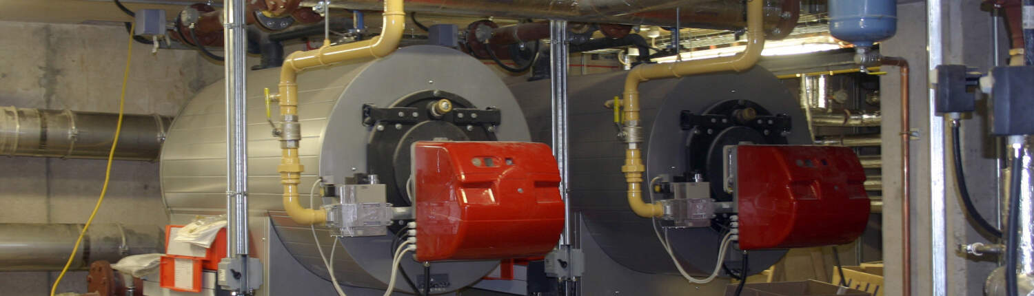 Side view of commercial boilers in a boiler room