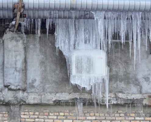 Front view of an air conditioning unit on the wall covered in ice