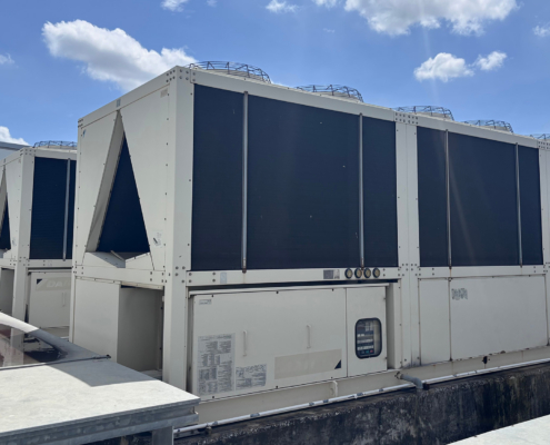 A row of large, modular commercial air-cooled chillers and HVAC units